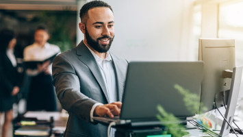 Photo of a man in an open-plan office who is responsible for technical support